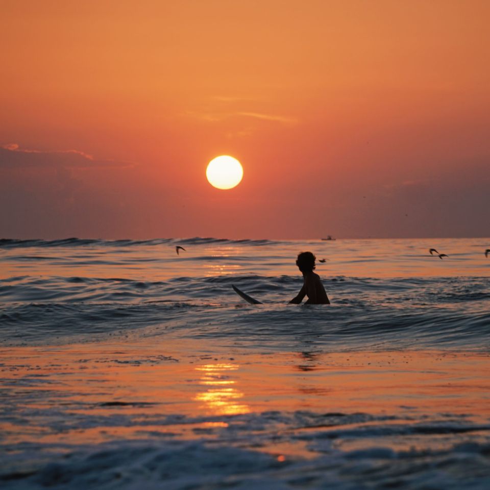 Surfera en su tabla disfrutando puesta sol en Tarifa